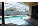 Screened-in swimming pool with clear water, surrounded by a paved deck and lush landscaping at 9003 Lido Ln, Port Richey, FL 34668