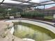 In ground pool with cage, showing the need for cleaning and some repairs at 9155 Pemberton St, Spring Hill, FL 34608