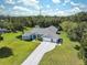 Aerial view of a charming one-story home with long driveway and well-manicured lawn, surrounded by lush trees at 9431 Amidon St, Spring Hill, FL 34608