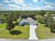 Aerial view of a charming one-story home with long driveway and well-manicured lawn, surrounded by lush trees at 9431 Amidon St, Spring Hill, FL 34608