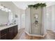 Bright bathroom featuring wood look flooring, a double vanity, and a walk-in shower with glass block window at 9431 Amidon St, Spring Hill, FL 34608