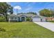 Charming single-story home boasts a manicured lawn, mature trees, and a three-car garage at 9431 Amidon St, Spring Hill, FL 34608