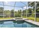 Relaxing screened-in pool and spa area with clear blue water, surrounded by lush greenery and black chain-link fence at 9431 Amidon St, Spring Hill, FL 34608