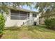 Lush backyard featuring a screened-in patio with stairs, green lawn, and mature landscaping at 1010 Teal Pointe, Tarpon Springs, FL 34689