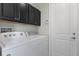 Laundry room with washer and dryer units, black cabinets, and white door at 1010 Teal Pointe, Tarpon Springs, FL 34689
