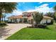Beautiful Mediterranean-style home features a three-car garage, circular driveway, lush landscaping, and a fountain at 10342 Altrara Way, Trinity, FL 34655