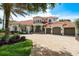 Attractive two-story Mediterranean-style home featuring a red tile roof, three-car garage, fountain, and meticulous landscaping at 10342 Altrara Way, Trinity, FL 34655