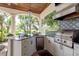 Outdoor kitchen with white cabinets, stainless steel grill, and view of lush tropical foliage at 10342 Altrara Way, Trinity, FL 34655