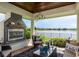 Covered outdoor patio with stone fireplace and views of the water at 10342 Altrara Way, Trinity, FL 34655