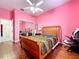 Bright pink bedroom with wood floors, mirrored closet, bed and fan at 10941 Hilltop Dr, New Port Richey, FL 34654
