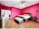Large bedroom with bright pink walls, hardwood floors, and a comfortable bed at 10941 Hilltop Dr, New Port Richey, FL 34654