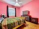Bright pink bedroom with wood floors, tv and dresser, bed and fan at 10941 Hilltop Dr, New Port Richey, FL 34654