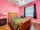 Bright pink bedroom with wood floors, window, bed and fan at 10941 Hilltop Dr, New Port Richey, FL 34654
