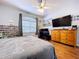 Bedroom featuring hardwood floors, fan, dresser, and large television at 10941 Hilltop Dr, New Port Richey, FL 34654