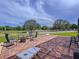 Brick patio area with outdoor seating, firepit, corn hole game, pasture view with white fence and trees at 10941 Hilltop Dr, New Port Richey, FL 34654