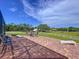 Outdoor brick patio area with corn hole game, outdoor seating, and a view of the expansive pasture at 10941 Hilltop Dr, New Port Richey, FL 34654