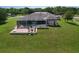 Aerial view of the backyard with large green yard, brick patio with furniture, and a screened pool area at 10941 Hilltop Dr, New Port Richey, FL 34654