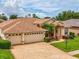 Inviting home exterior featuring a three-car garage, paver driveway, and lush landscaping at 11144 Brambleleaf Way, Hudson, FL 34667