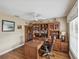 This spacious office features wood floors, a ceiling fan, a large window and custom built-in shelving at 11144 Brambleleaf Way, Hudson, FL 34667