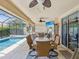 Inviting outdoor patio with a screened-in pool, dining table, ceiling fans, and comfortable seating area, perfect for relaxation at 11144 Brambleleaf Way, Hudson, FL 34667