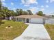 Home exterior featuring a long driveway, front yard, and white garage door at 11280 Sedgefield Ave, Spring Hill, FL 34608