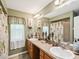 Bathroom featuring dual sinks, a large mirror, and tub-shower combo with decorative palm tree shower curtain at 12229 Barnevelde Rd, Weeki Wachee, FL 34614