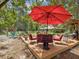 Relaxing wooden deck featuring a red umbrella, outdoor seating, and a view of the outdoor fireplace at 12229 Barnevelde Rd, Weeki Wachee, FL 34614
