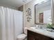 Bathroom featuring a dark vanity with granite top, decorative mirror and shower with white curtain at 12323 House Finch, Weeki Wachee, FL 34614