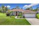 Charming home showcasing a well-manicured lawn, complemented by a red front door and a two-car garage at 12323 House Finch, Weeki Wachee, FL 34614