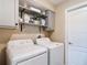 Laundry room with gray cabinets, decorative shelving, and a washer and dryer at 12323 House Finch, Weeki Wachee, FL 34614