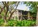Exterior view of a two-story home featuring screened in lanais on both floors surrounded by lush greenery at 13009 Wedgewood Way # 63-D, Hudson, FL 34667