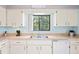 Traditional kitchen featuring white cabinets, a stainless steel sink, and a window offering a green view at 13009 Wedgewood Way # 63-D, Hudson, FL 34667