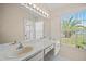 Bathroom featuring dual sinks, a large mirror with vanity lighting, and a window at 13491 Coronado Dr, Spring Hill, FL 34609