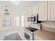 Bright kitchen nook featuring large windows, white cabinets, stainless steel appliances, and tile flooring at 13491 Coronado Dr, Spring Hill, FL 34609