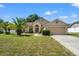 Inviting single-Gathering home featuring a well-kept lawn with palm trees, a two-car garage, and traditional architecture at 13491 Coronado Dr, Spring Hill, FL 34609