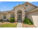 Close-up of home's front entrance, showcasing an arched doorway, sidelights, and manicured landscaping at 13491 Coronado Dr, Spring Hill, FL 34609
