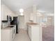 Light-filled kitchen with stainless appliances, white cabinets, and a breakfast bar looking into the living room at 13491 Coronado Dr, Spring Hill, FL 34609