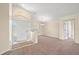 Bright living room with neutral carpet, white trim, and an entryway with a transom window above the front door at 13491 Coronado Dr, Spring Hill, FL 34609
