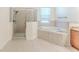 Bright bathroom with a soaking tub and glass enclosed shower with tan colored tile at 13772 Dunwoody Dr, Spring Hill, FL 34609