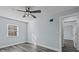 Bright bedroom features wood-look floors, a ceiling fan, and a wall-mounted TV bracket at 13821 Judy Ave, Hudson, FL 34667