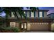 Two-story home at twilight featuring blue shutters, mature landscaping, and brick driveway at 1410 Halapa Way, Trinity, FL 34655