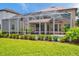 View of the screened-in pool and patio with outdoor furniture and well-manicured lawn at 1410 Halapa Way, Trinity, FL 34655