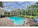 Beautiful screened-in pool with brick surround, lounge chairs, and lush greenery in the backyard at 1410 Halapa Way, Trinity, FL 34655