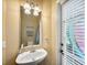 Convenient powder room featuring a pedestal sink, decorative mirror and good light from the window at 1410 Halapa Way, Trinity, FL 34655