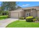 Charming single-story home with manicured lawn, neutral color palette, and attached two car garage at 1415 Pinewood Hills Ct, Spring Hill, FL 34606