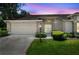 Charming single-story home with manicured lawn, neutral color palette, and attached two car garage at 1415 Pinewood Hills Ct, Spring Hill, FL 34606
