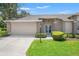 Charming single-story home with manicured lawn, neutral color palette, and attached two car garage at 1415 Pinewood Hills Ct, Spring Hill, FL 34606