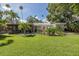 View of home's spacious green backyard with a screened in porch and tropical landscaping at 1830 Santa Barbara Dr, Dunedin, FL 34698