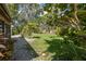 Lush backyard featuring well-maintained lawn and diverse tropical landscaping with a gravel walkway at 1830 Santa Barbara Dr, Dunedin, FL 34698