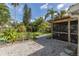 Serene backyard oasis with lush tropical foliage, a screened-in lanai, and a tranquil gravel area at 1830 Santa Barbara Dr, Dunedin, FL 34698